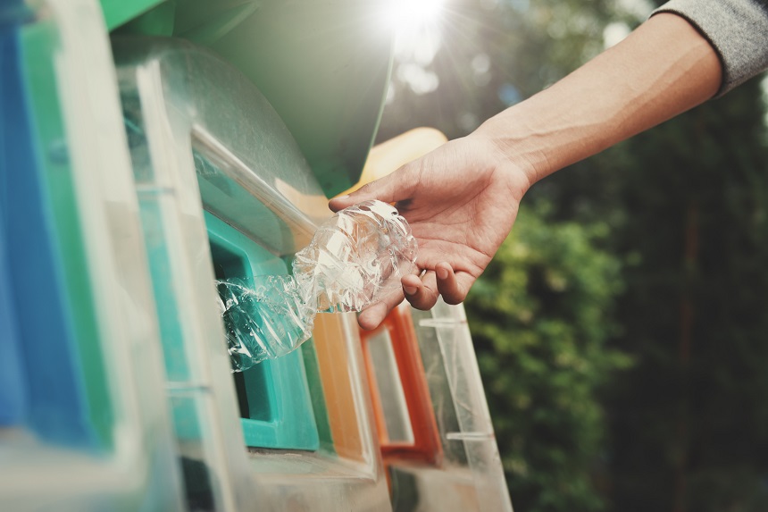 people putting plastic bottle in to recycle bin at park
